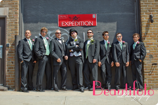 The groom and his men pose in front of a wharehouse garage door