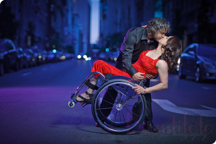 the couple kissing the bride in the wheelchair while the groom dips the bride to be in the streets of Montreal.