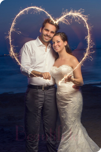 bride and groom drawing a hear with sparklers