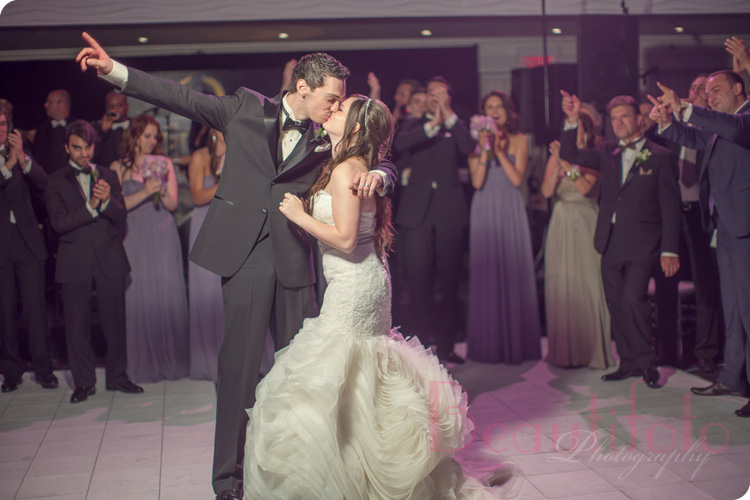 bride and groom kissing on the dance floor as they enter the reception hall