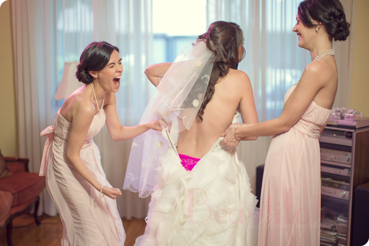 A funny moment with the bride and her maid of honor while she puts on the wedding dress
