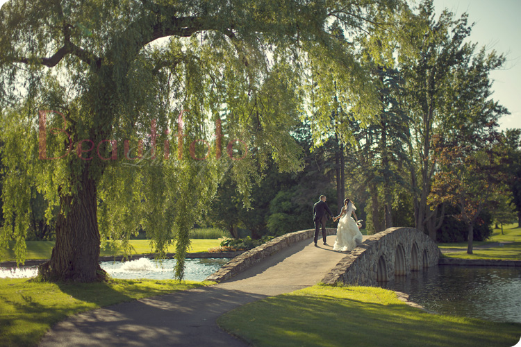 epic wedding shot of the bride and groom crossing a bridge