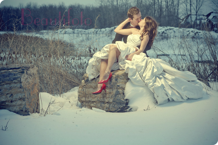 Bride and groom kissing on a rock with snow during a winter trash the dress session