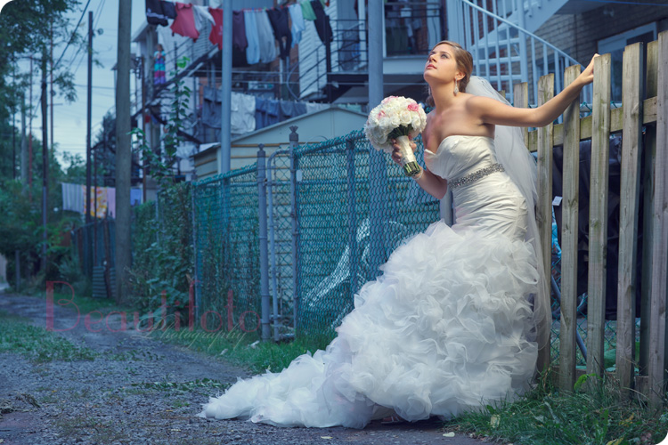 Bride holding her flower bouquet next to a fence