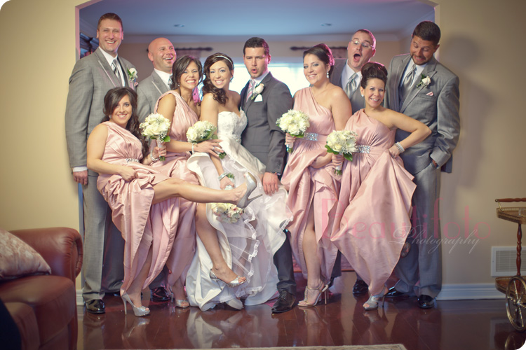 A portrait of the bridal party having fun with the bridesmaids wearing pink dresses