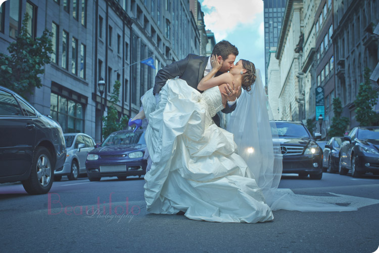 The bride and groom kissing in traffic in the street of down town Montreal