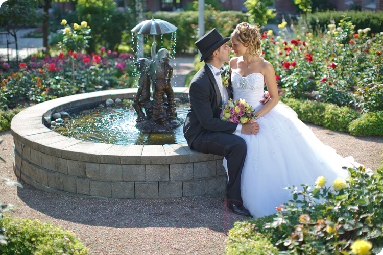 the bride and groom posing by the water fountain